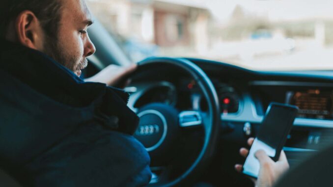 person holding and staring a phone at the wheel of an audi vehicle.jpg